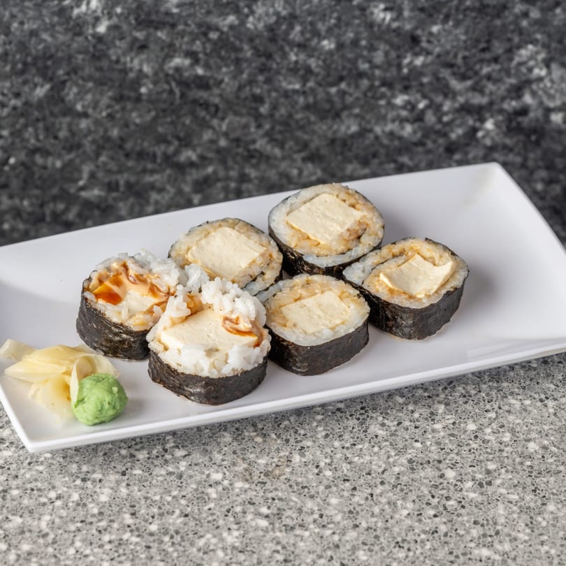 Six pieces of sushi with tofu, rice, and seaweed, served with ginger and wasabi.