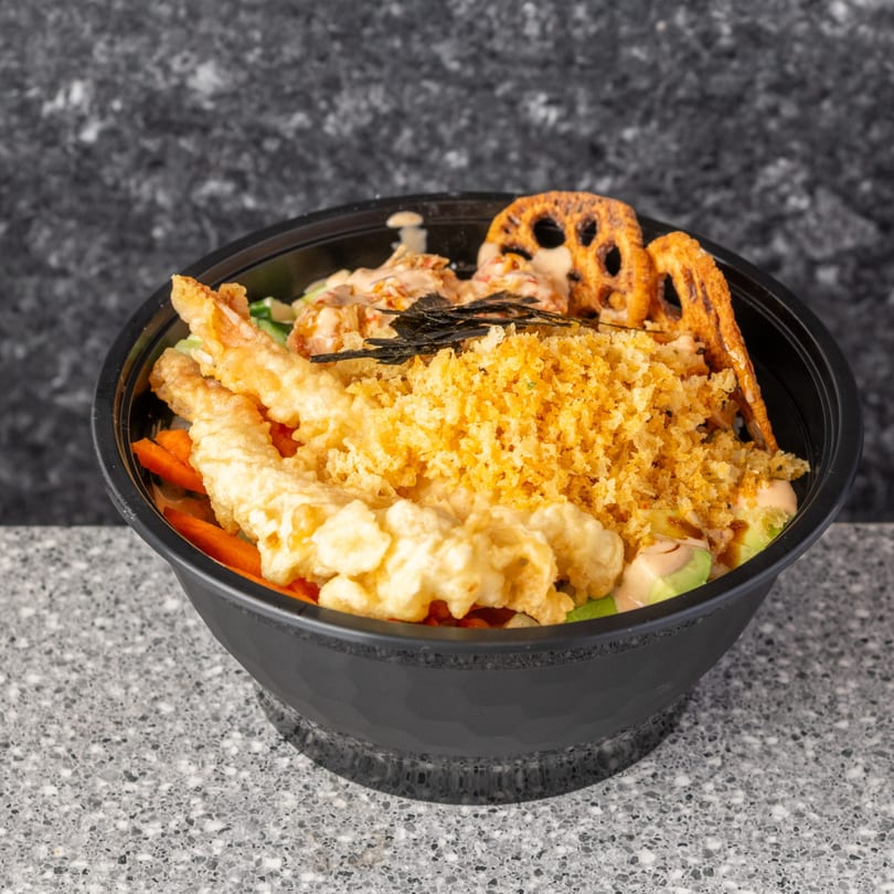 Wrap & Roll sushi bowl with tempura shrimp, crispy lotus root, and avocado on a speckled counter.